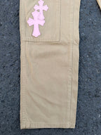 Beige pants with large pink cross applique on upper leg