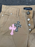 Beige pants close-up of button waistband and cross appliqué patch