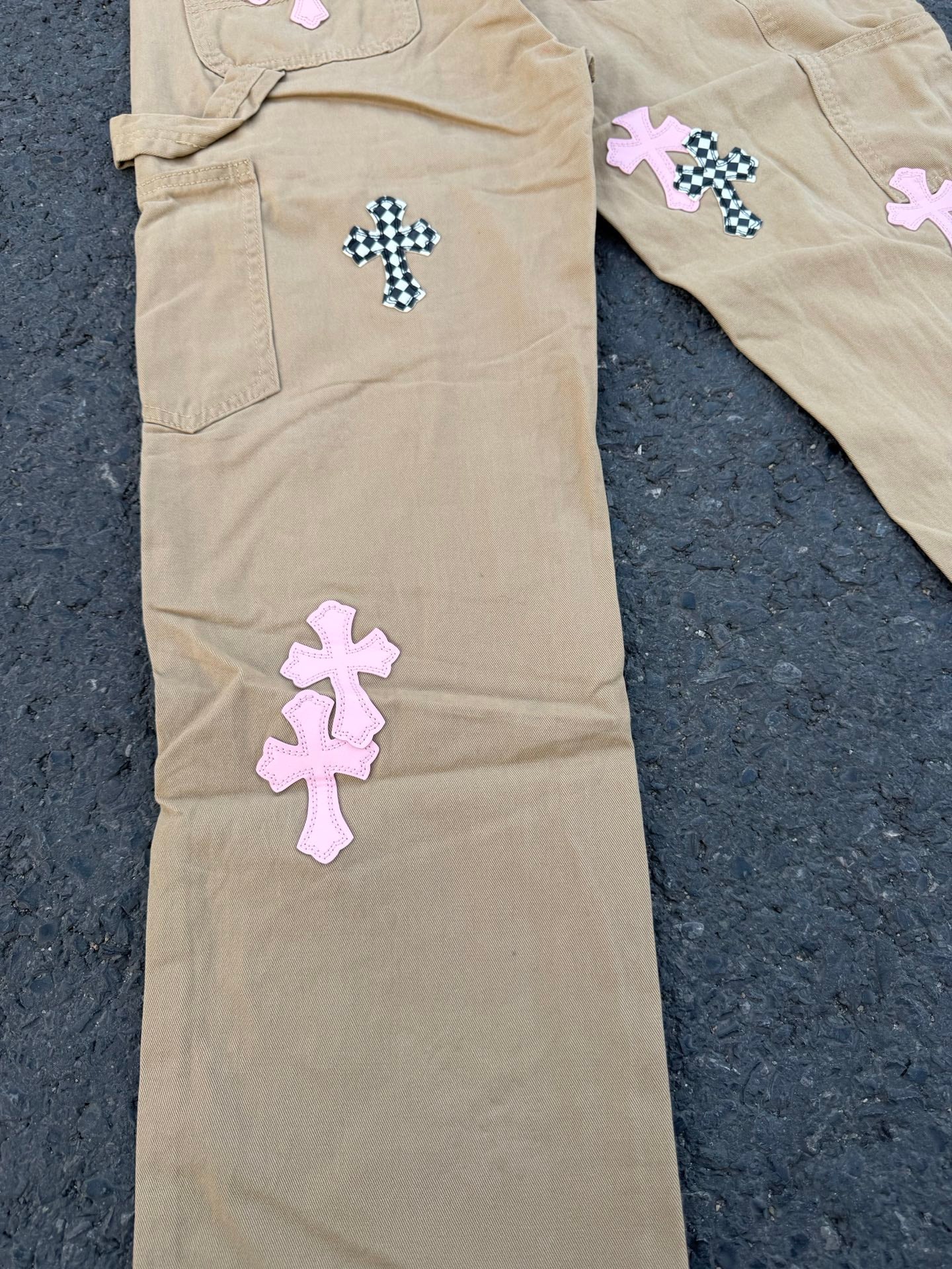 Beige pants leg with small cross patches on pocket and front