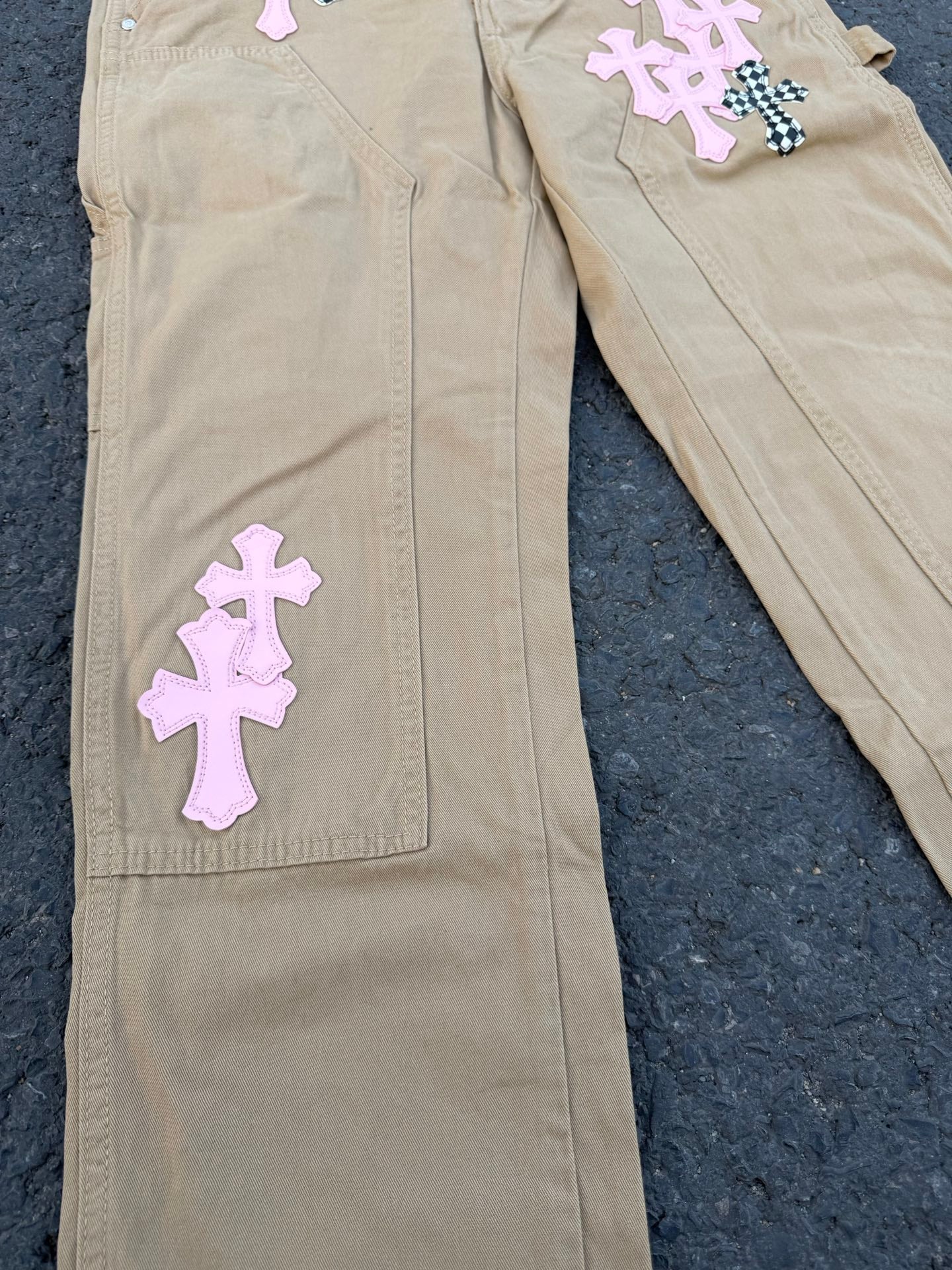 Beige pants front close-up with purple cross patches on leg pockets