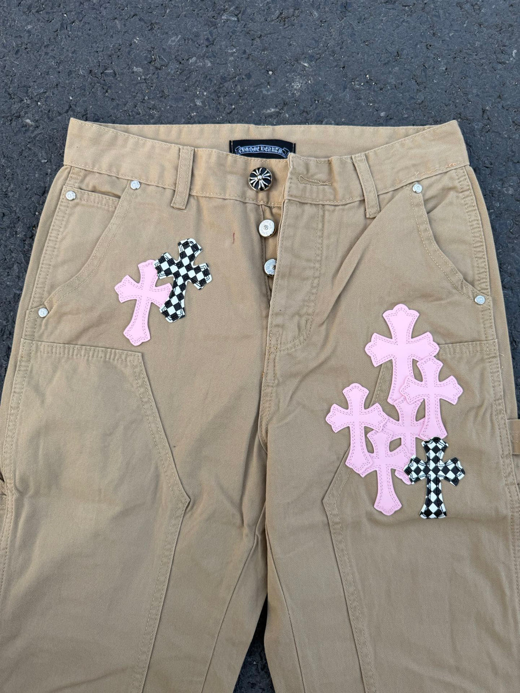 Beige pants front with snap button closure and cross appliqué patches