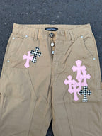 Beige pants front with snap button closure and cross appliqué patches
