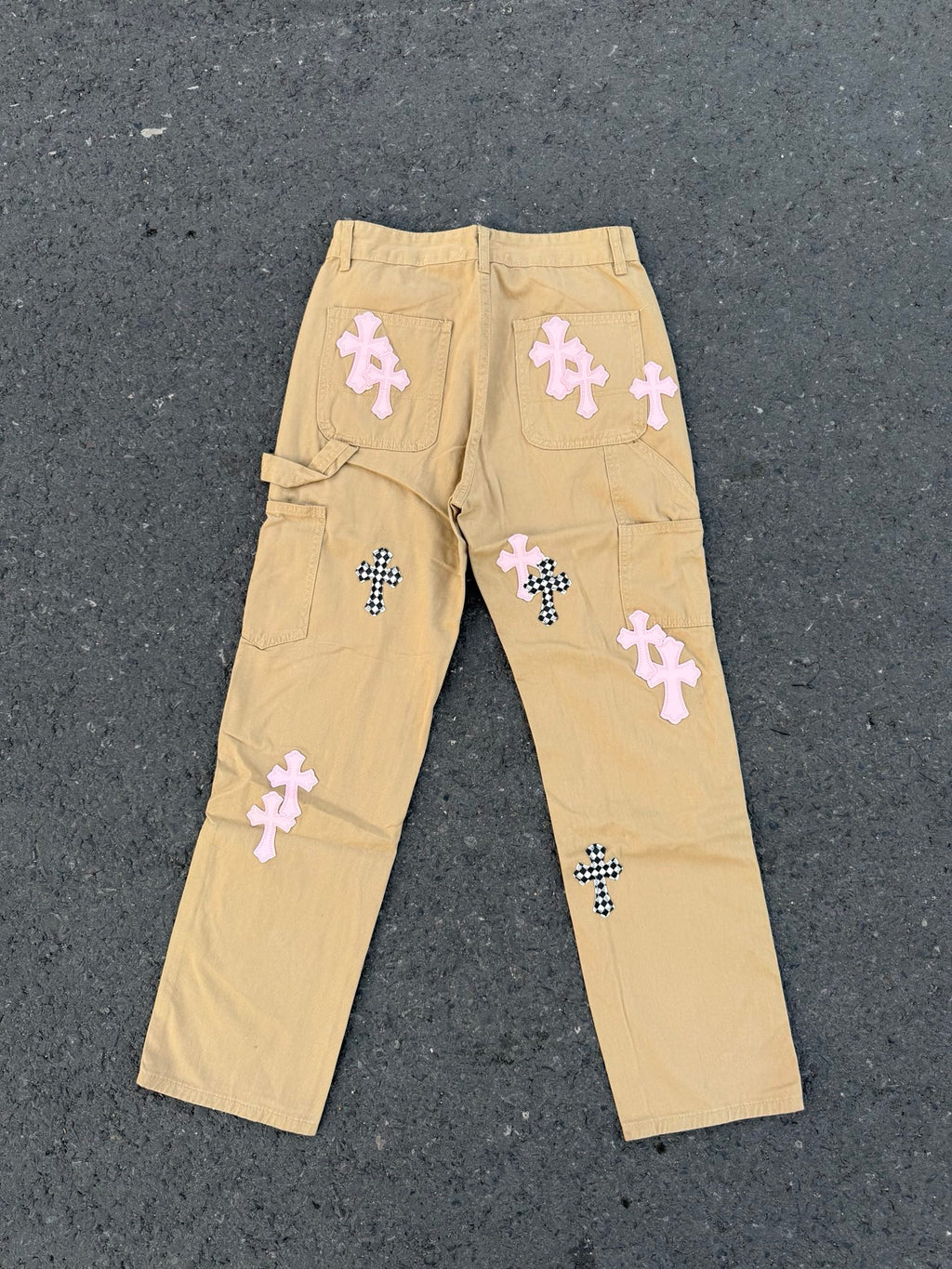 Beige straight-leg pants with multiple embroidered cross patches