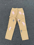 Beige straight-leg pants with multiple embroidered cross patches