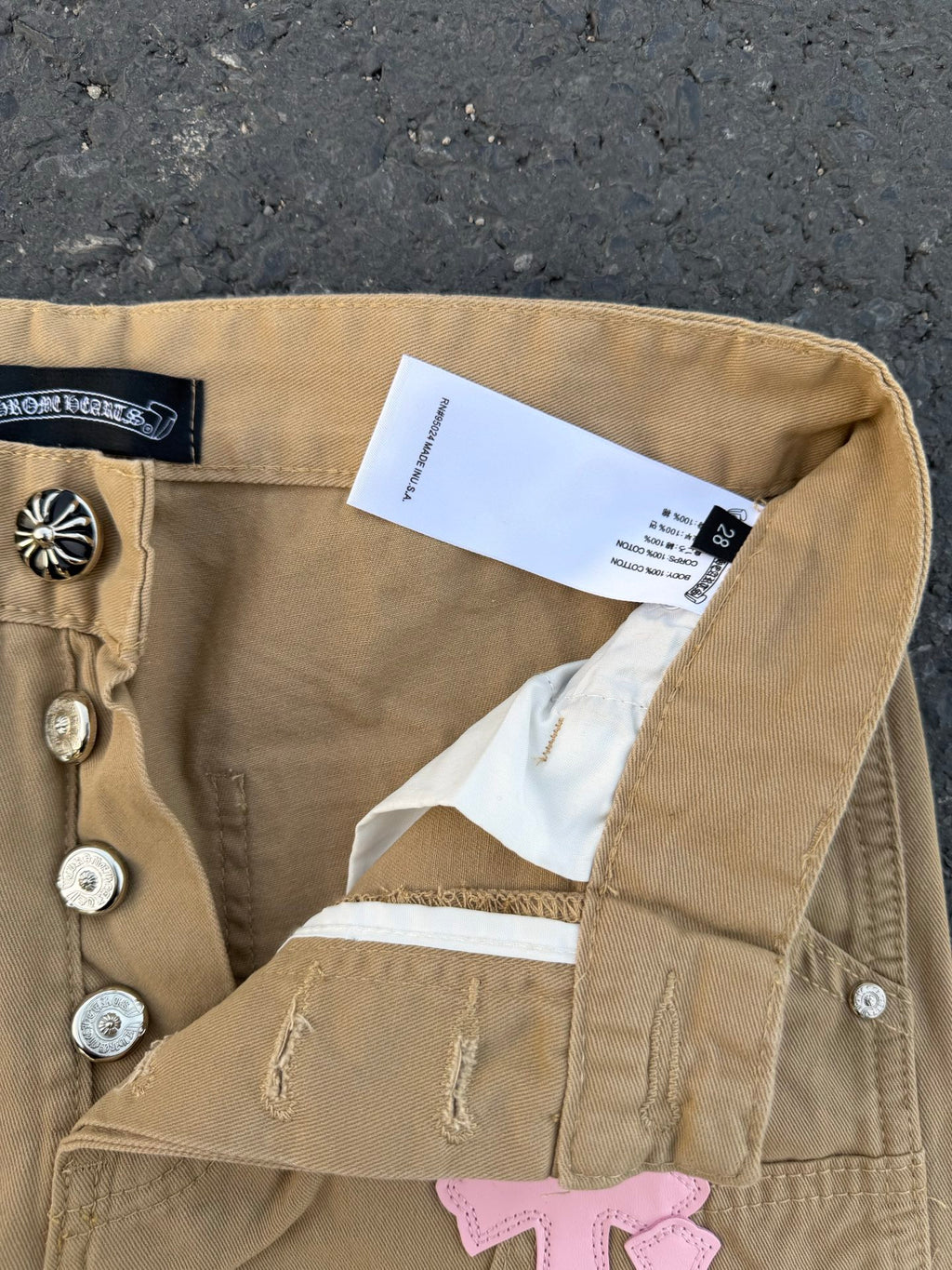 Beige pants close-up of back waistband and care label near snap buttons
