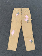 Beige cargo pants with embroidered cross patches and snap fly front
