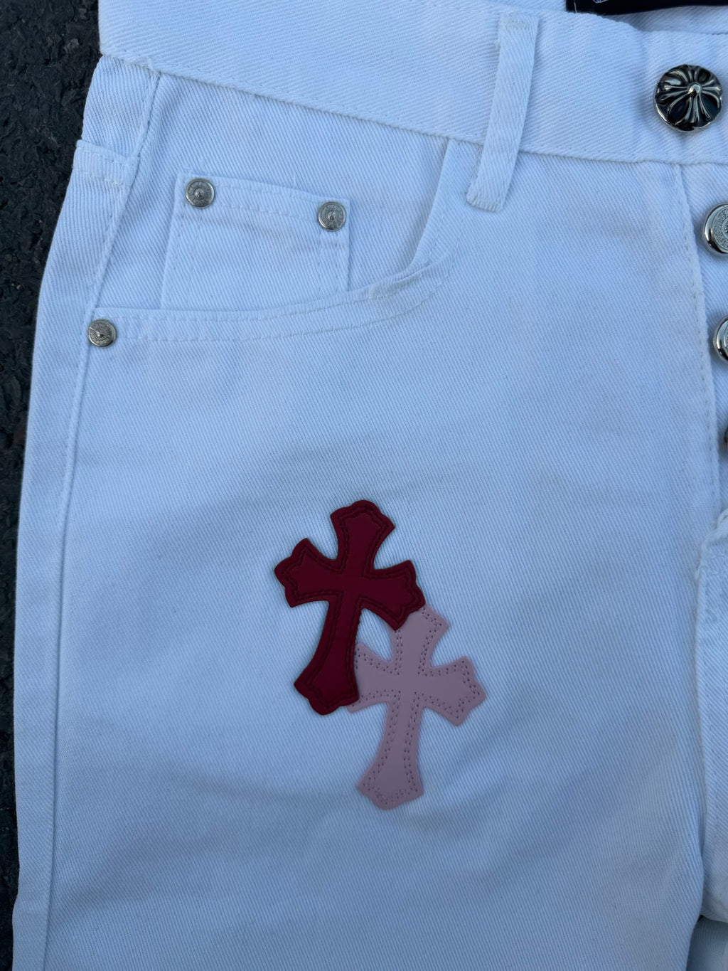 Light blue pants with red cross and gray cross applique near pocket and zipper
