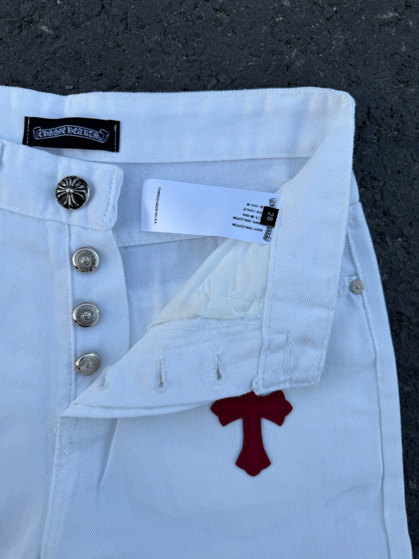 Light blue pants close-up with buttons, belt loops, and red cross graphic