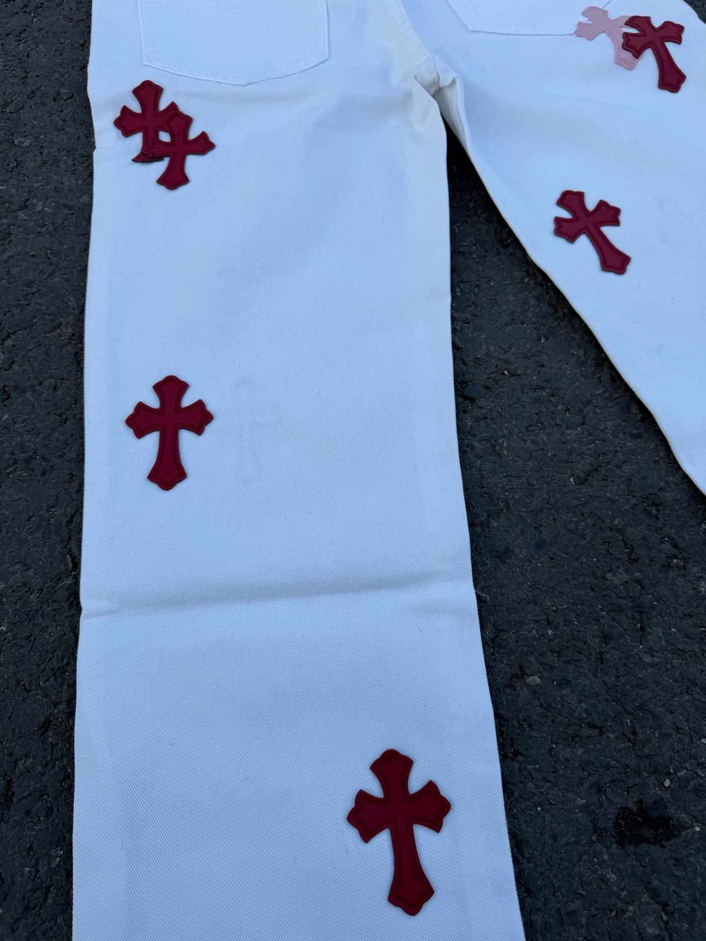 Light blue pants with scattered red cross prints on one side leg