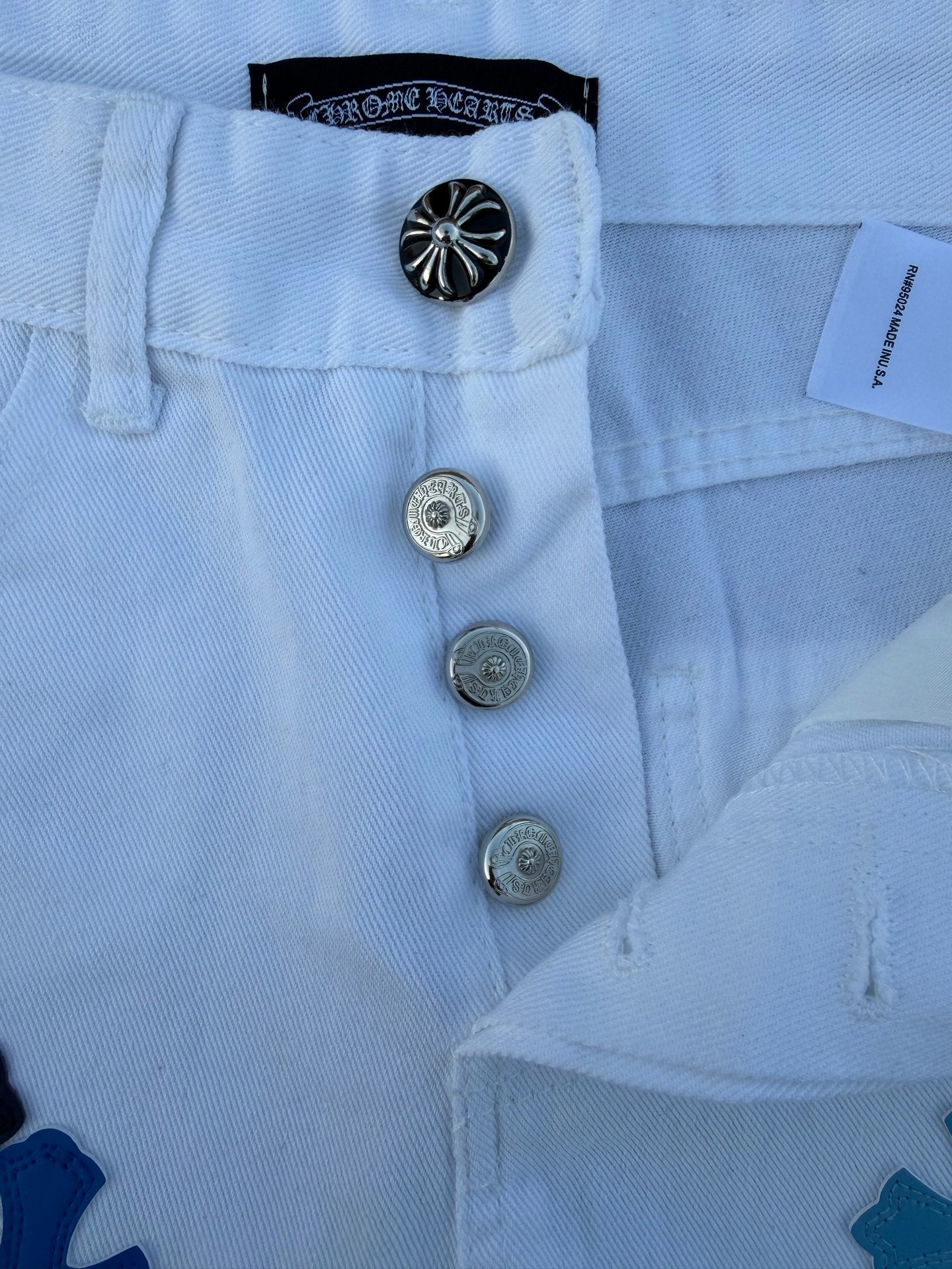 Light blue pants with navy cross print, button front and belt loops close-up