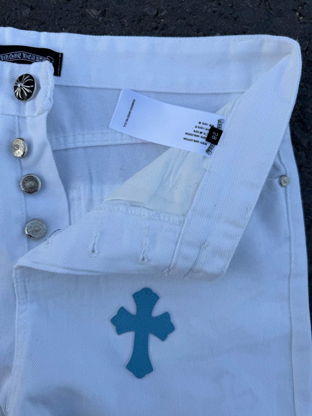 Light blue pants with navy cross print, waistband and snap buttons close-up