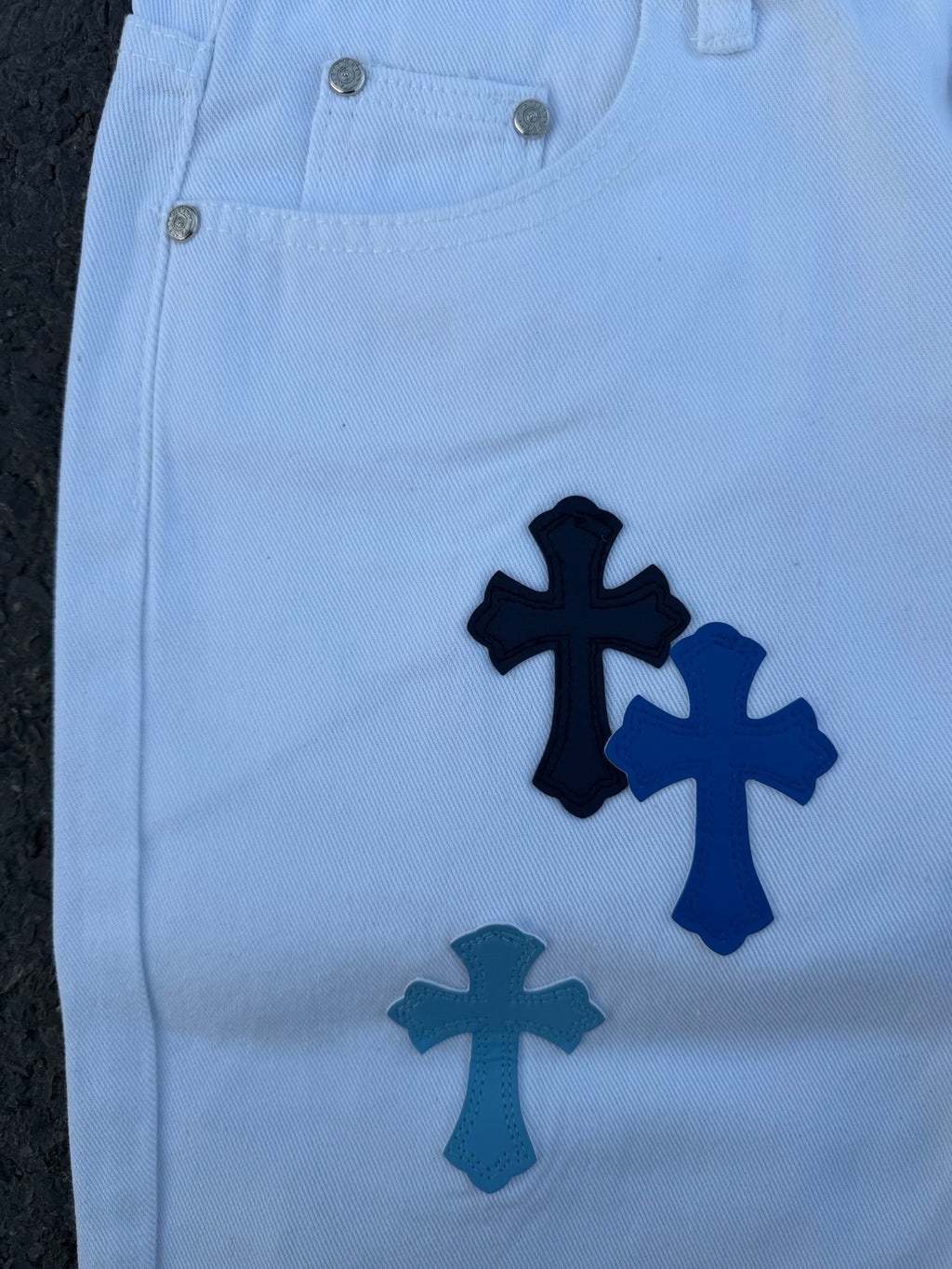 Light blue pants with navy cross applique print, front close-up