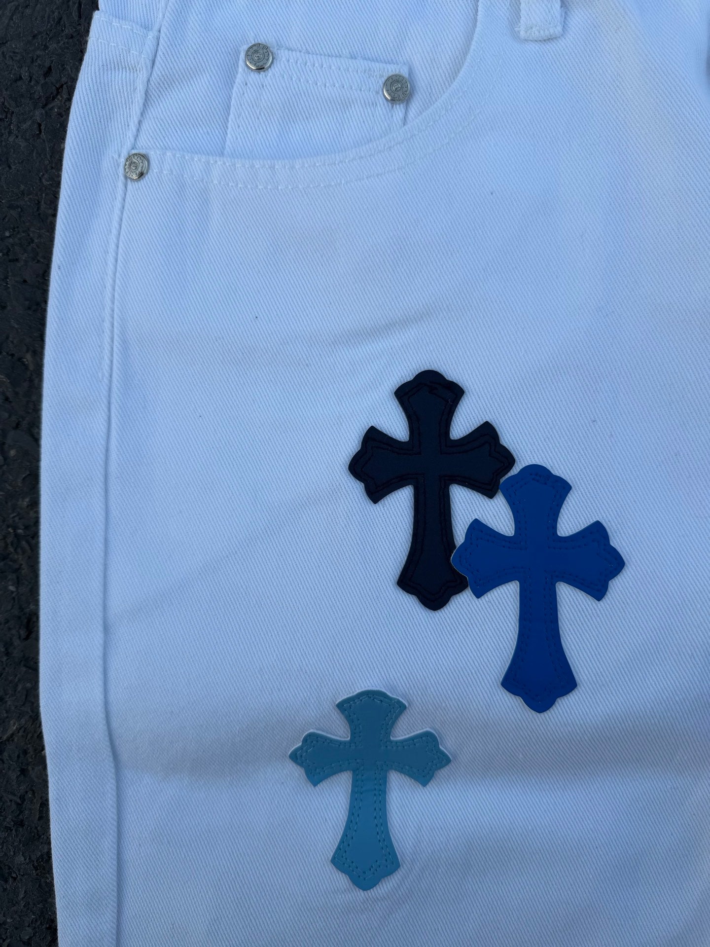 Light blue pants with navy cross applique print, front close-up