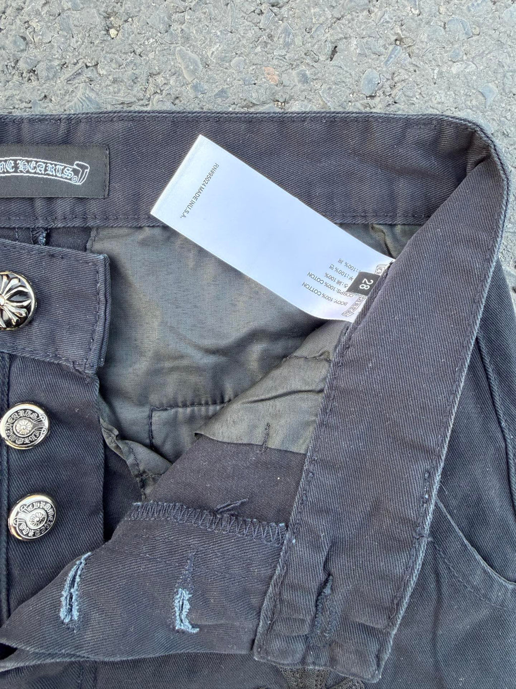 Dark gray pants showing button closure, interior tag, and side seam pocket