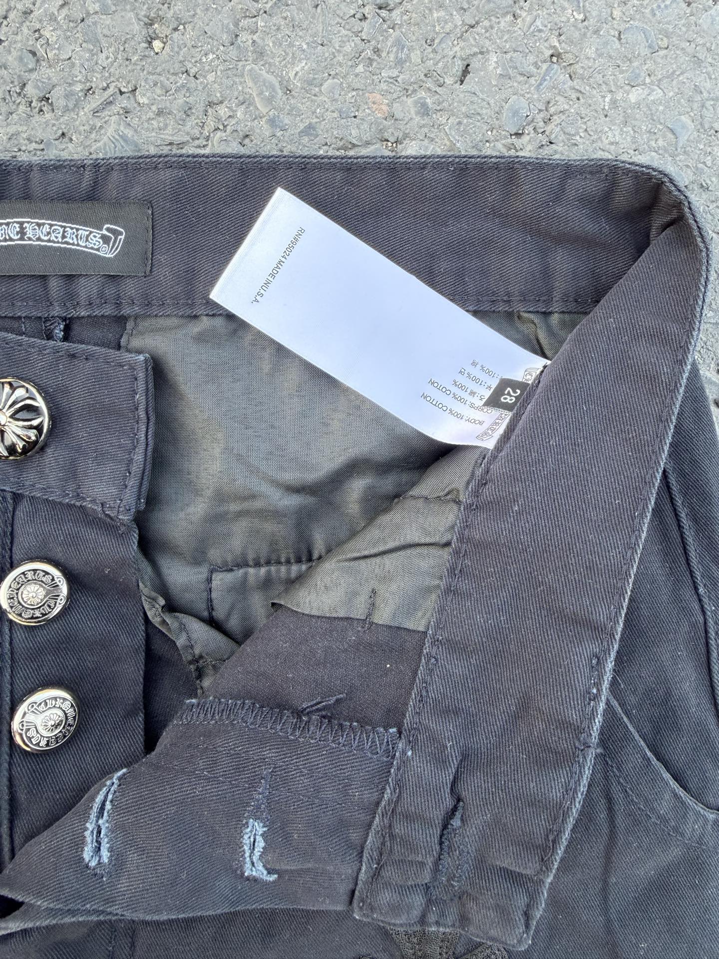 Dark gray pants showing button closure, interior tag, and side seam pocket