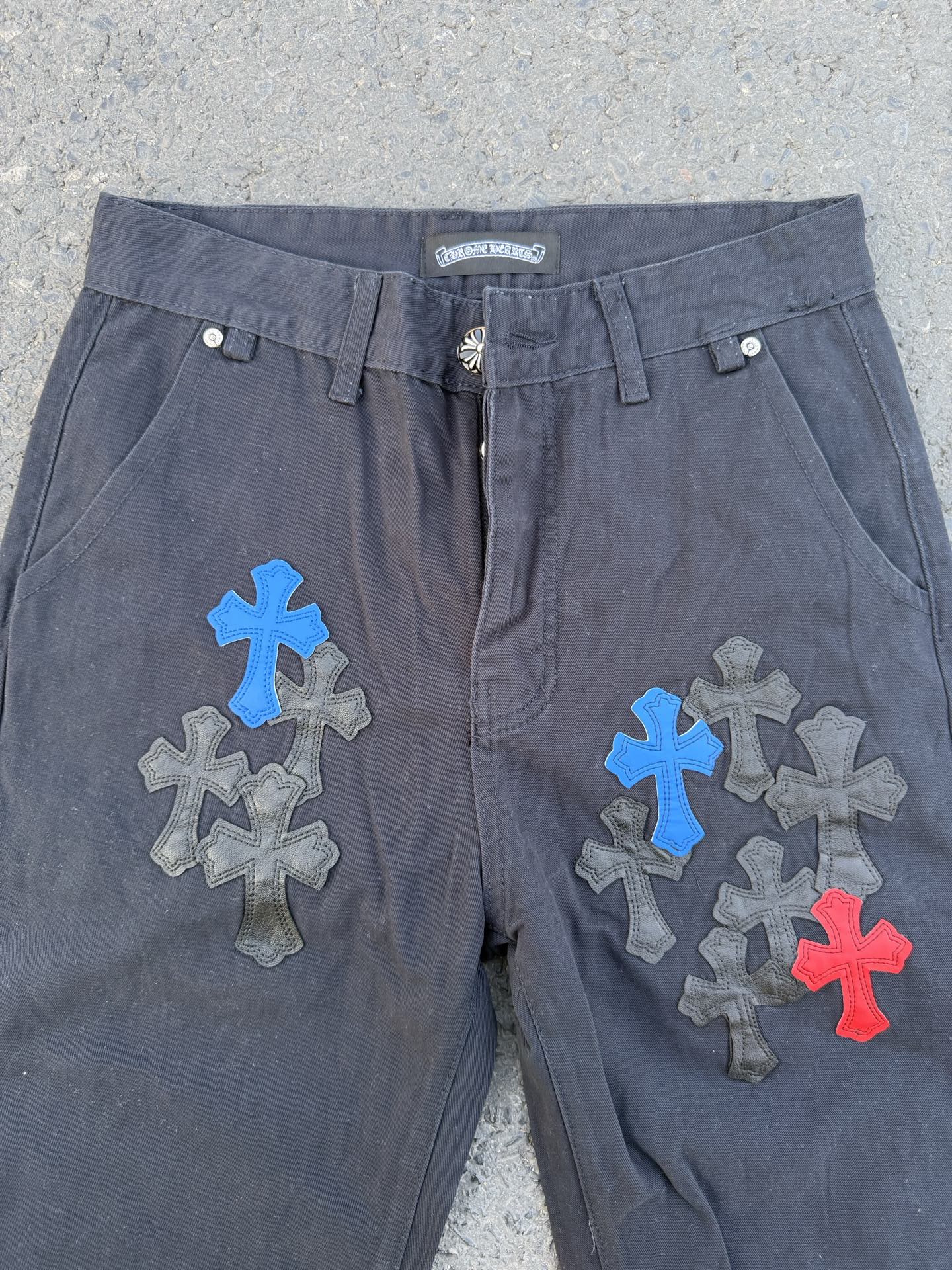 Dark gray pants with front fly and large blue, gray, and red cross patches