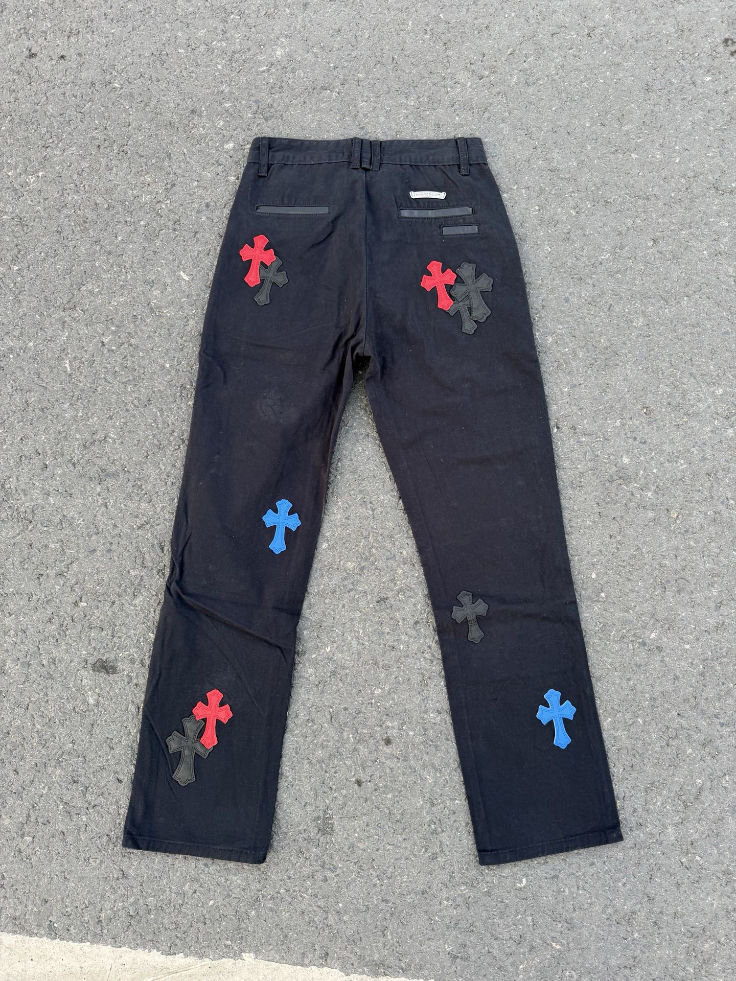 Dark gray straight-leg pants with colorful cross patches and back pocket details