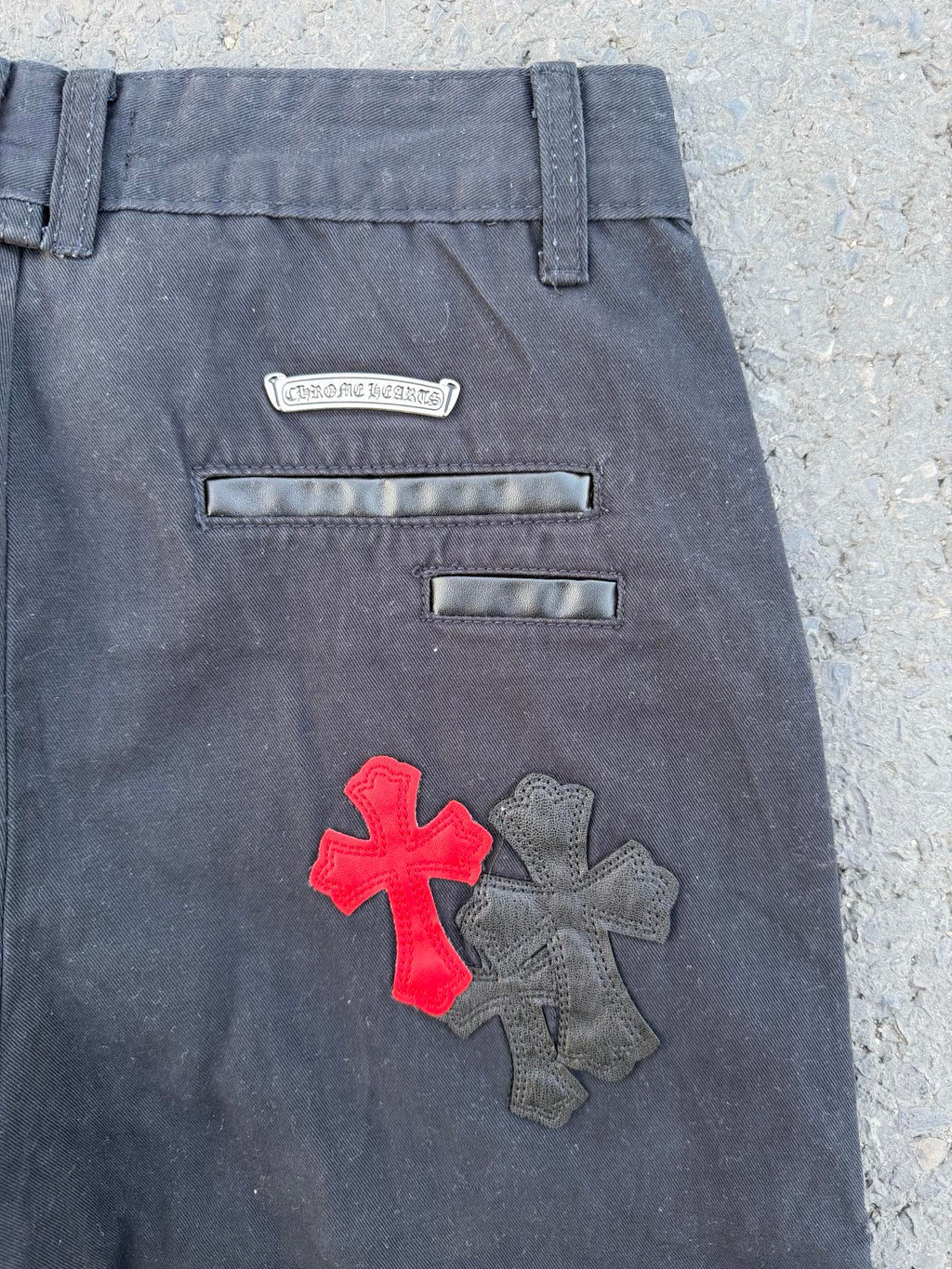 Dark gray pants back close-up with embroidered cross patch and two horizontal pockets