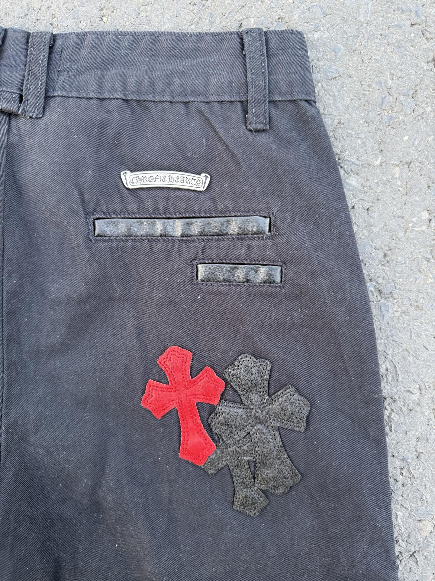 Dark gray pants back close-up with embroidered cross patch and two horizontal pockets