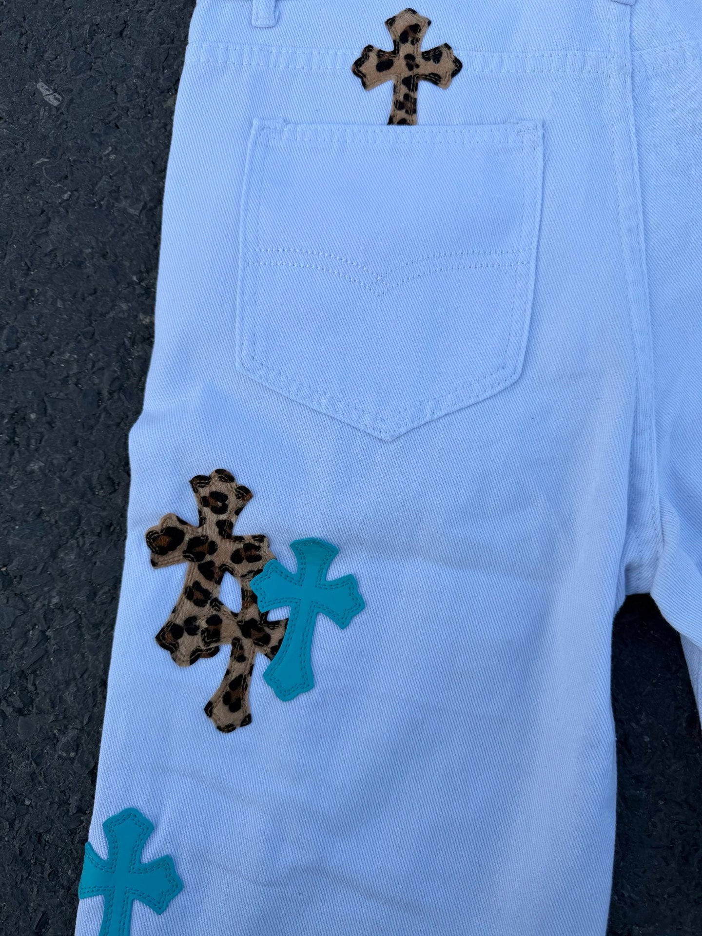 Light blue back of pants with one cross applique near pocket