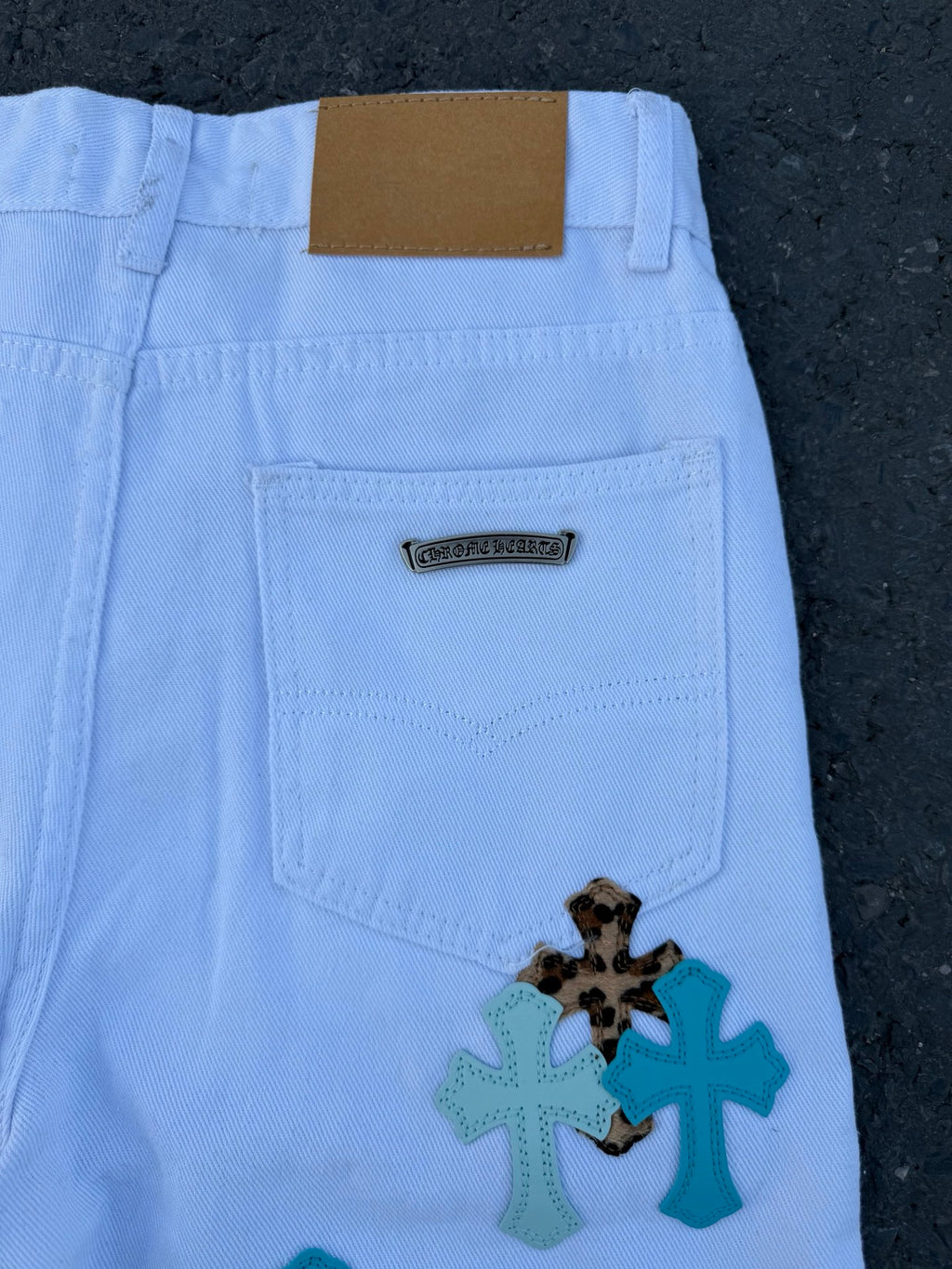 Light blue pants back panel with patch label and cross applique near pocket