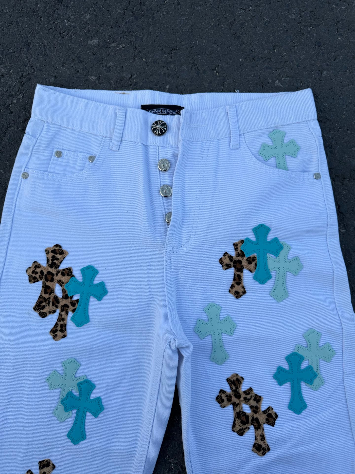 Light blue pants with button-and-zip fly and cross appliques on legs