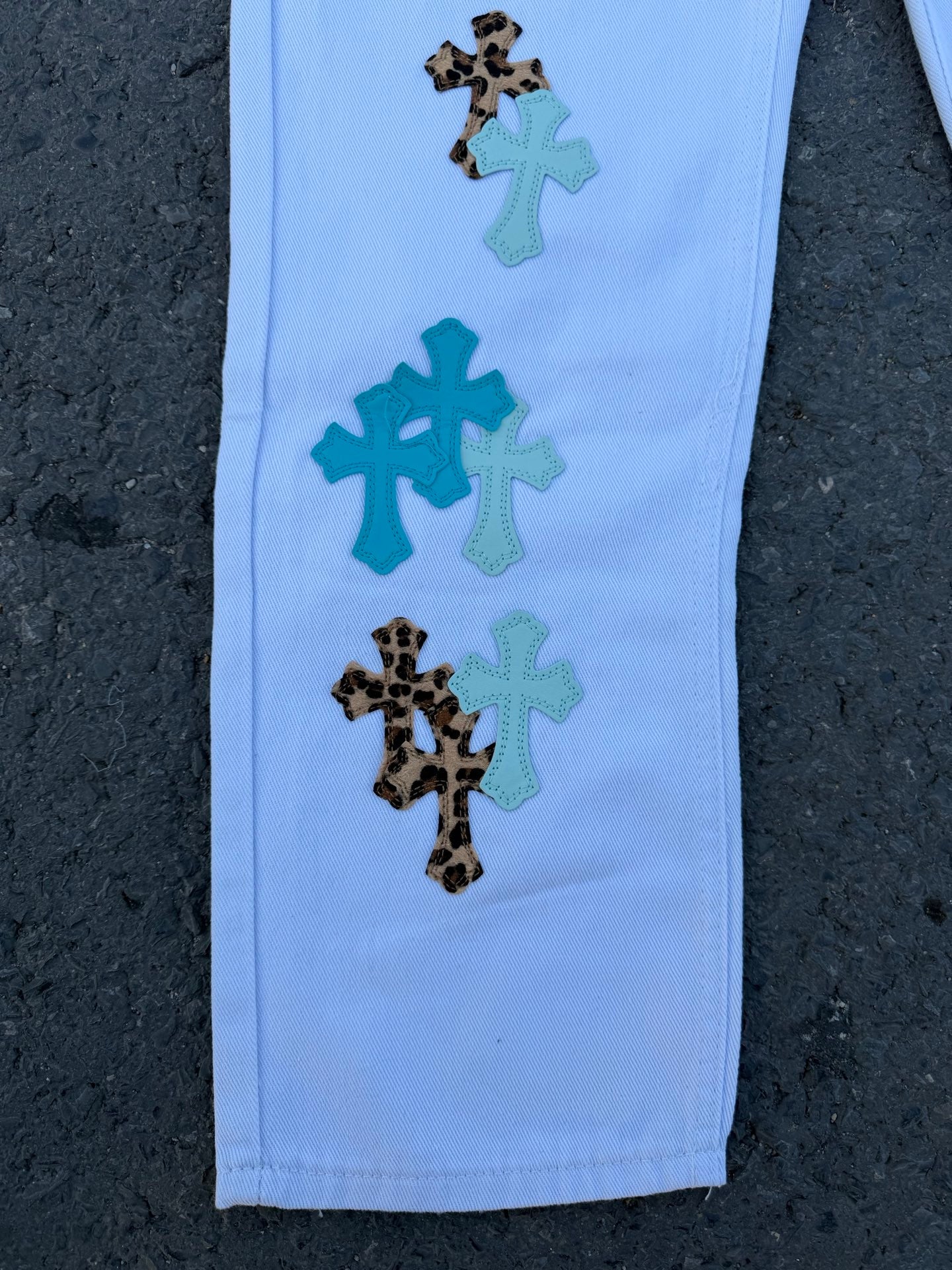 Light blue pants with teal and black patterned appliqué stars and flowers