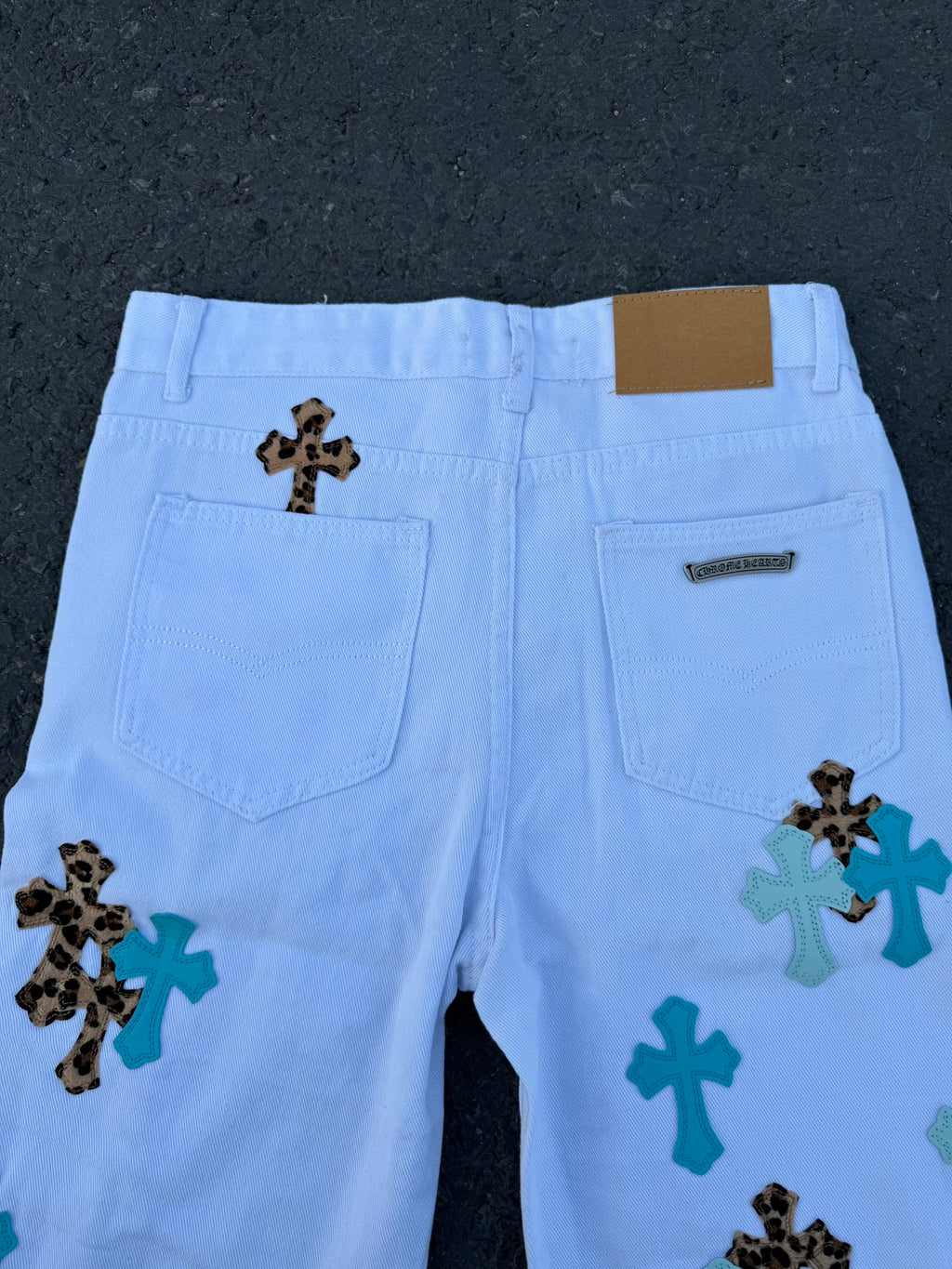 Light blue pants with back pockets and cross applique graphics