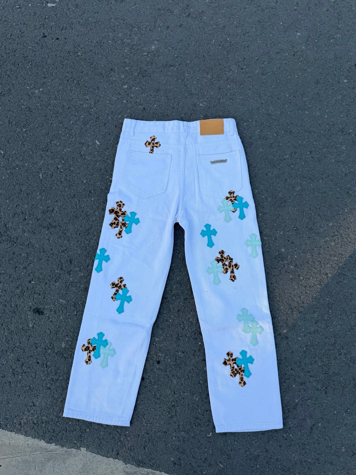 Light blue straight-leg pants with scattered cross appliques on the front