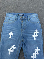 Light blue denim jeans with white cross patches, front waistband view.