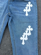 Light blue denim jeans with white cross patches along the leg, side seam detail.