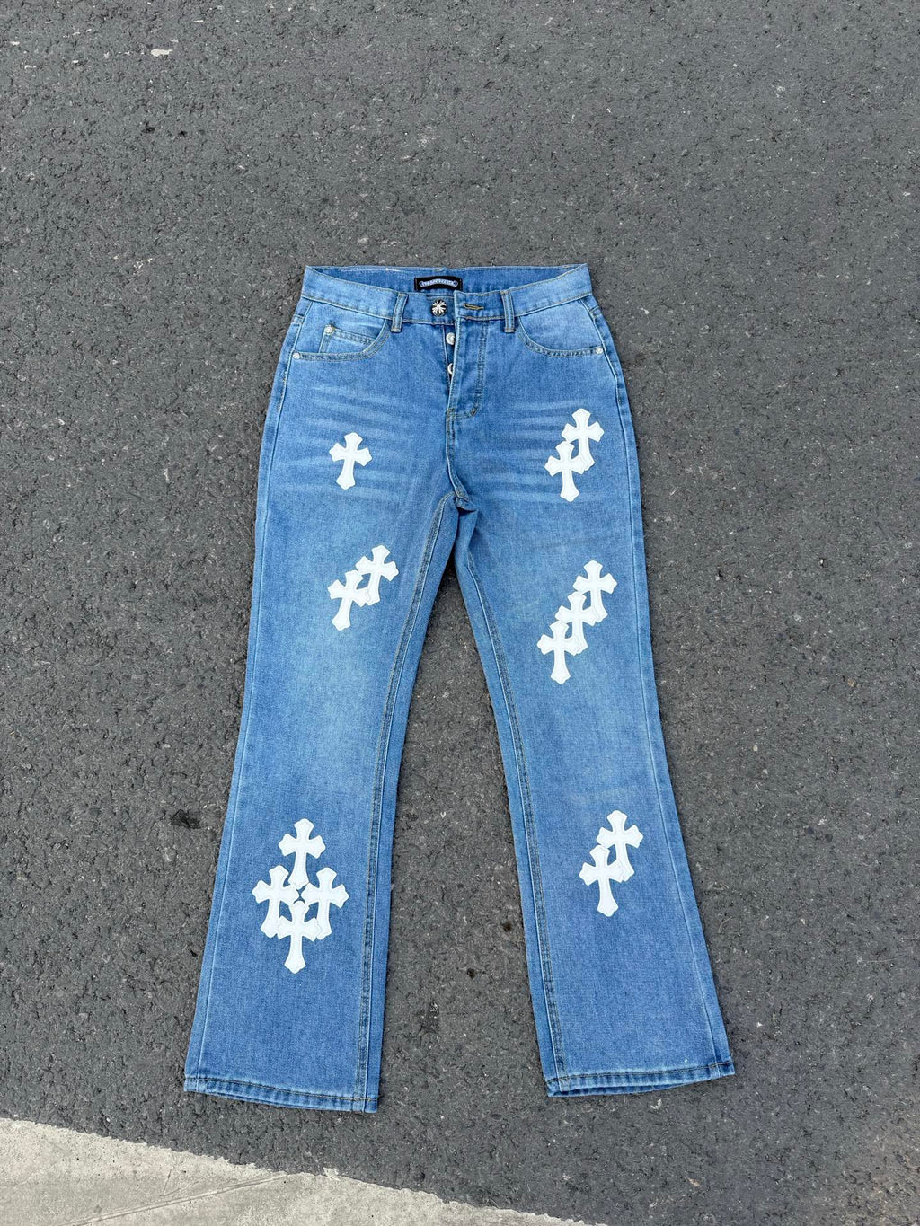 Light blue denim jeans with white cross patches, straight leg.