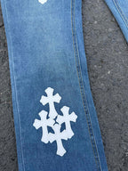 Light blue denim pants with white cross patch on leg