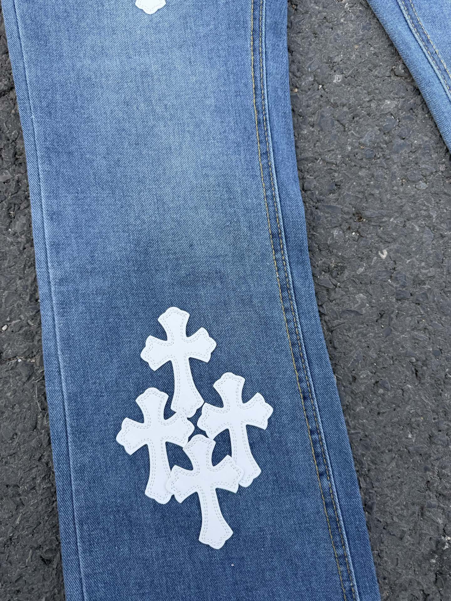 Light blue denim pants with white cross patch on leg