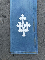 Light blue denim pants with white cross-stitch patch near hem