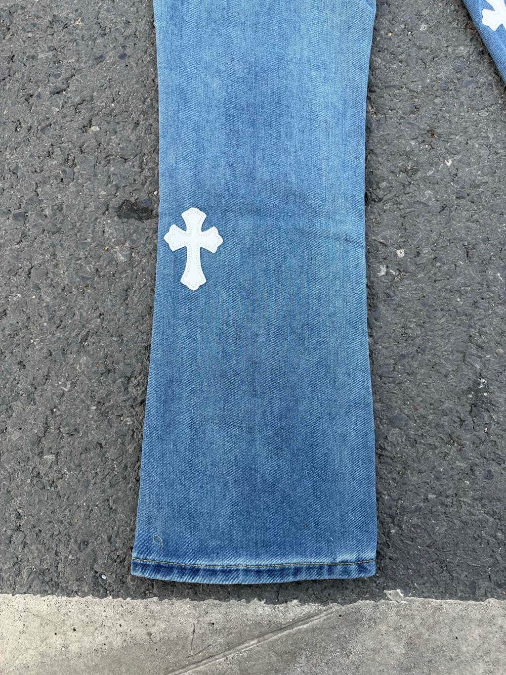Light blue denim pants with small white cross patch on side