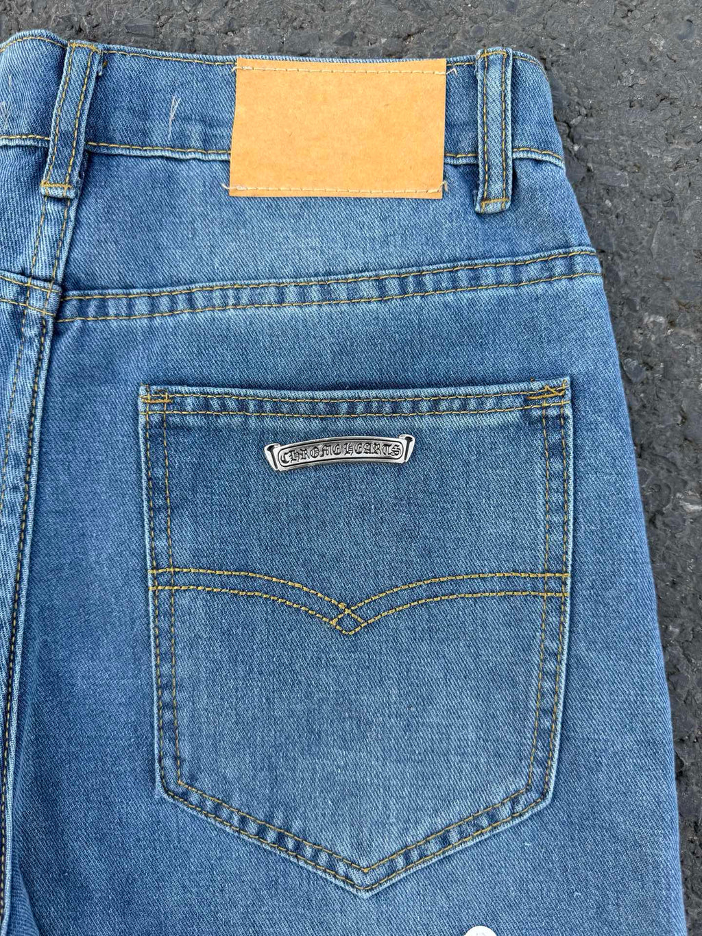 Light blue denim jeans back waistband with heart-shaped pocket, orange tag.