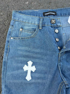 Light blue denim jeans with front pocket, white cross patch, button details.