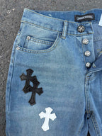 Light blue denim pants with black and white cross patches on the front leg
