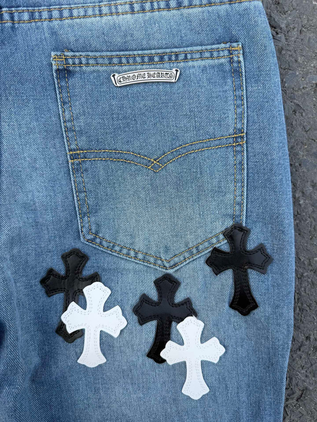 Back pocket of light blue denim pants with label and cross patches below