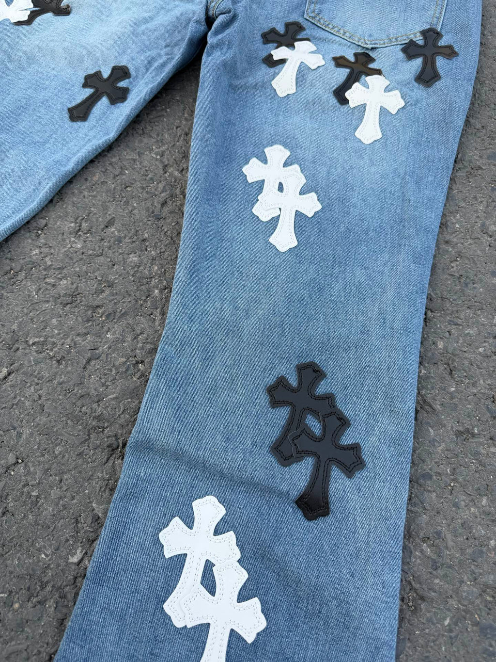 Light blue denim pants with cross graphic patches on the leg