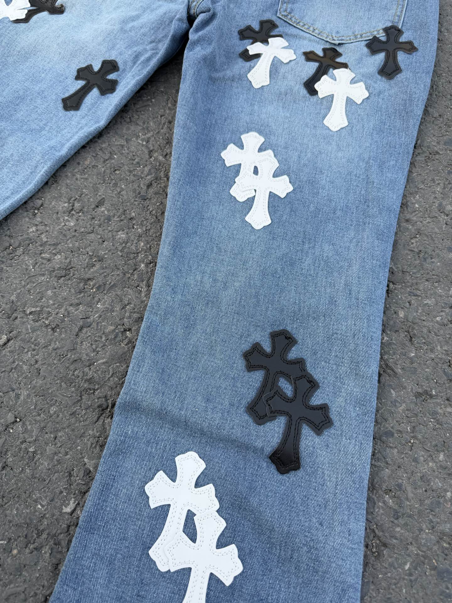 Light blue denim pants with cross graphic patches on the leg