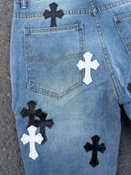 Close-up of back of light blue denim pants with heart pocket and cross patches