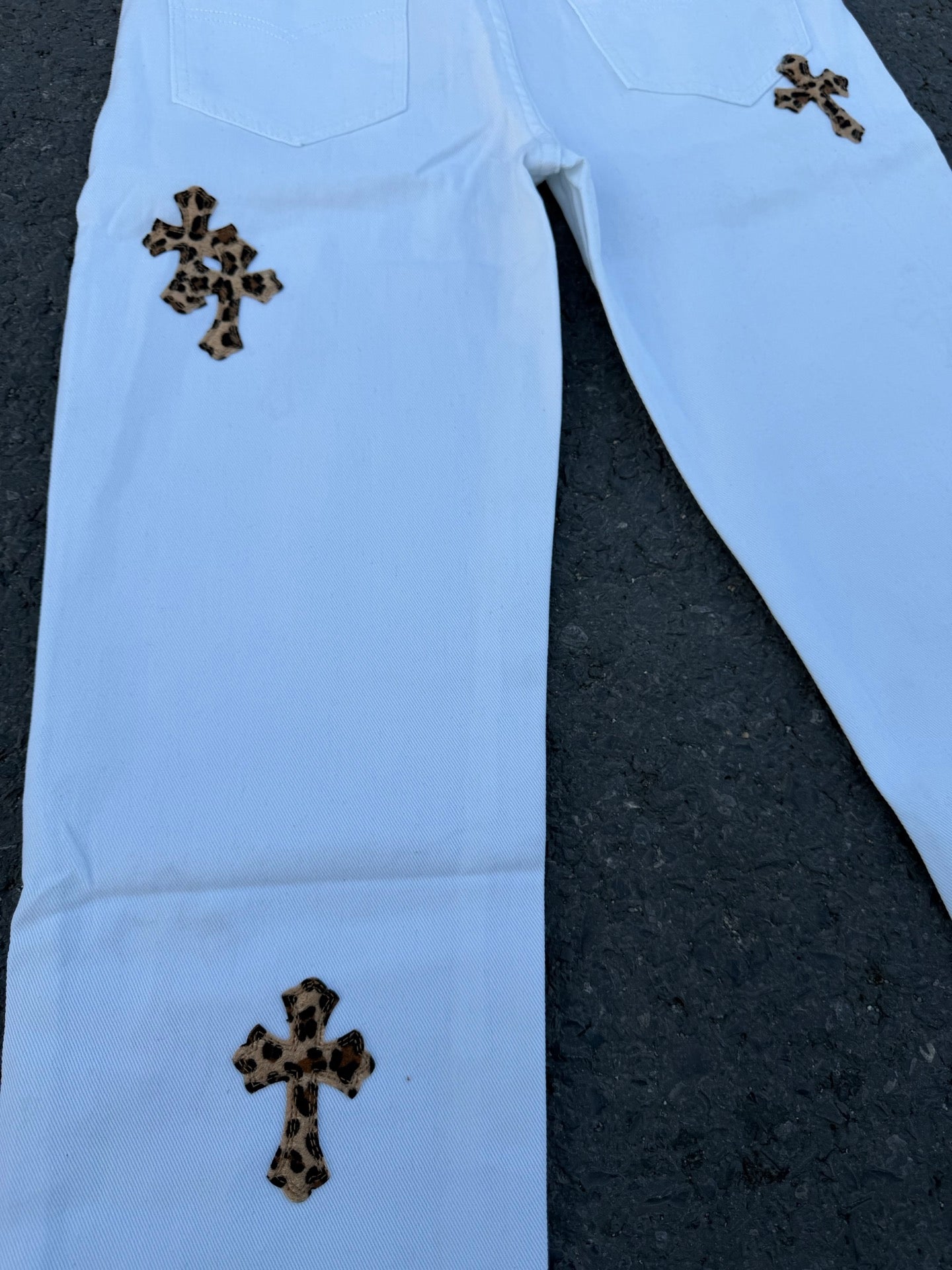 Light blue straight pants with dark cross patches on legs and two front pockets