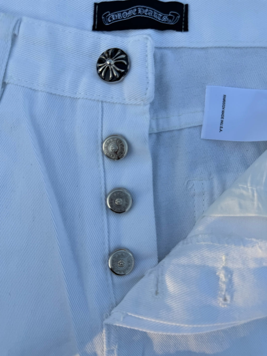 Light blue pants detail: button fly, metal buttons, and circular logo patch