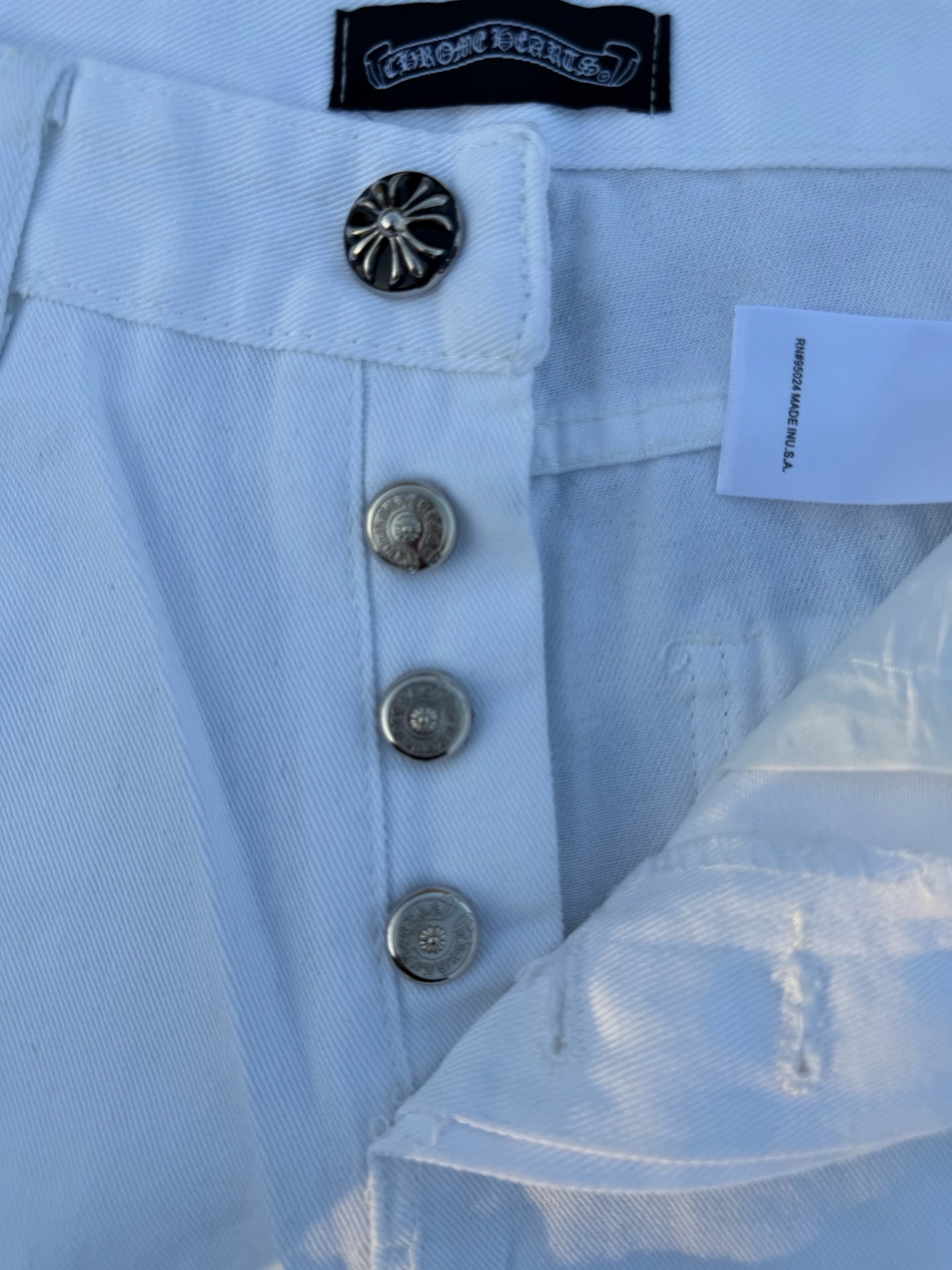 Light blue pants detail: button fly, metal buttons, and circular logo patch