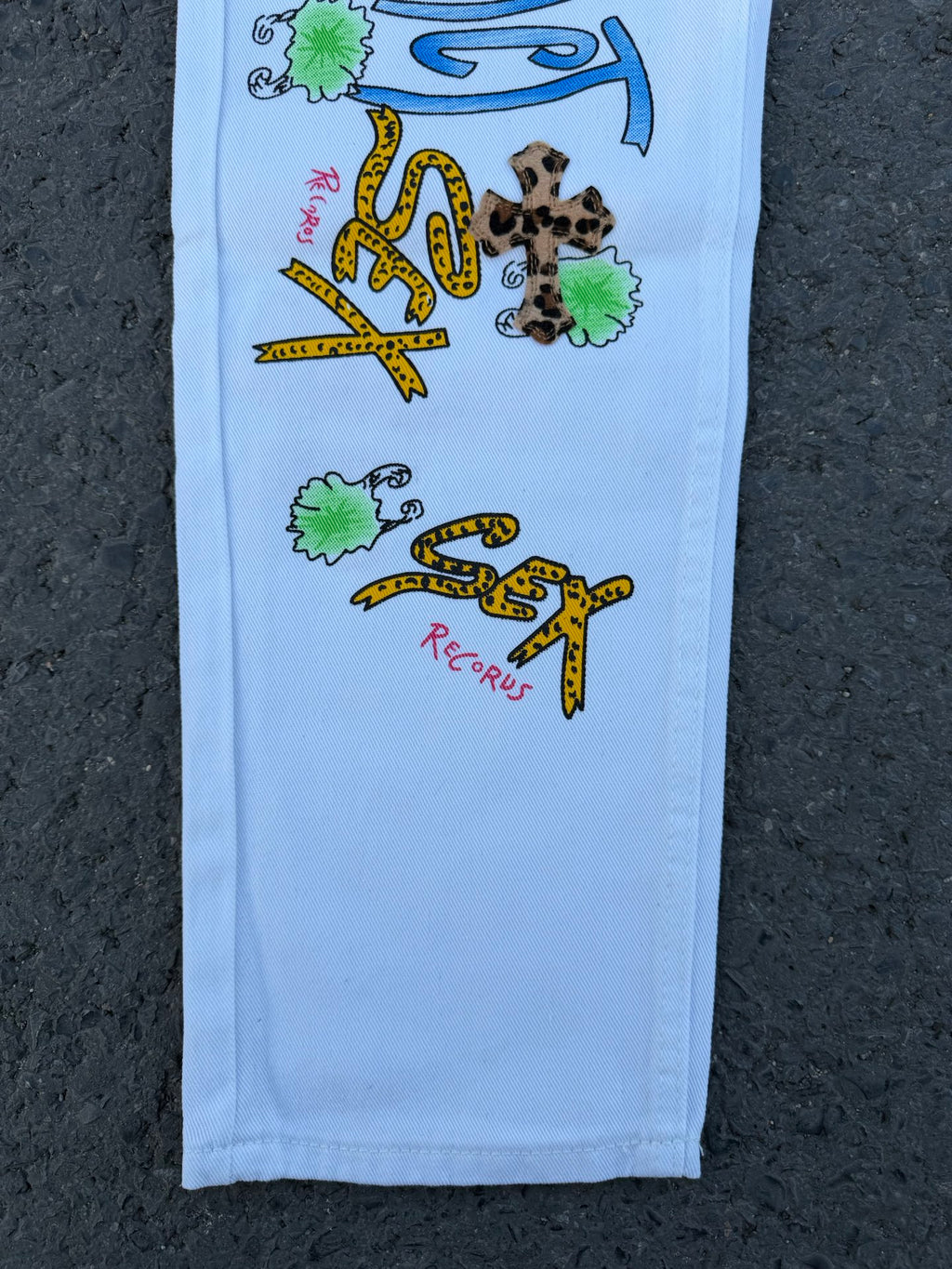 Light blue pants with centered colorful graffiti-style print and small leopard designs
