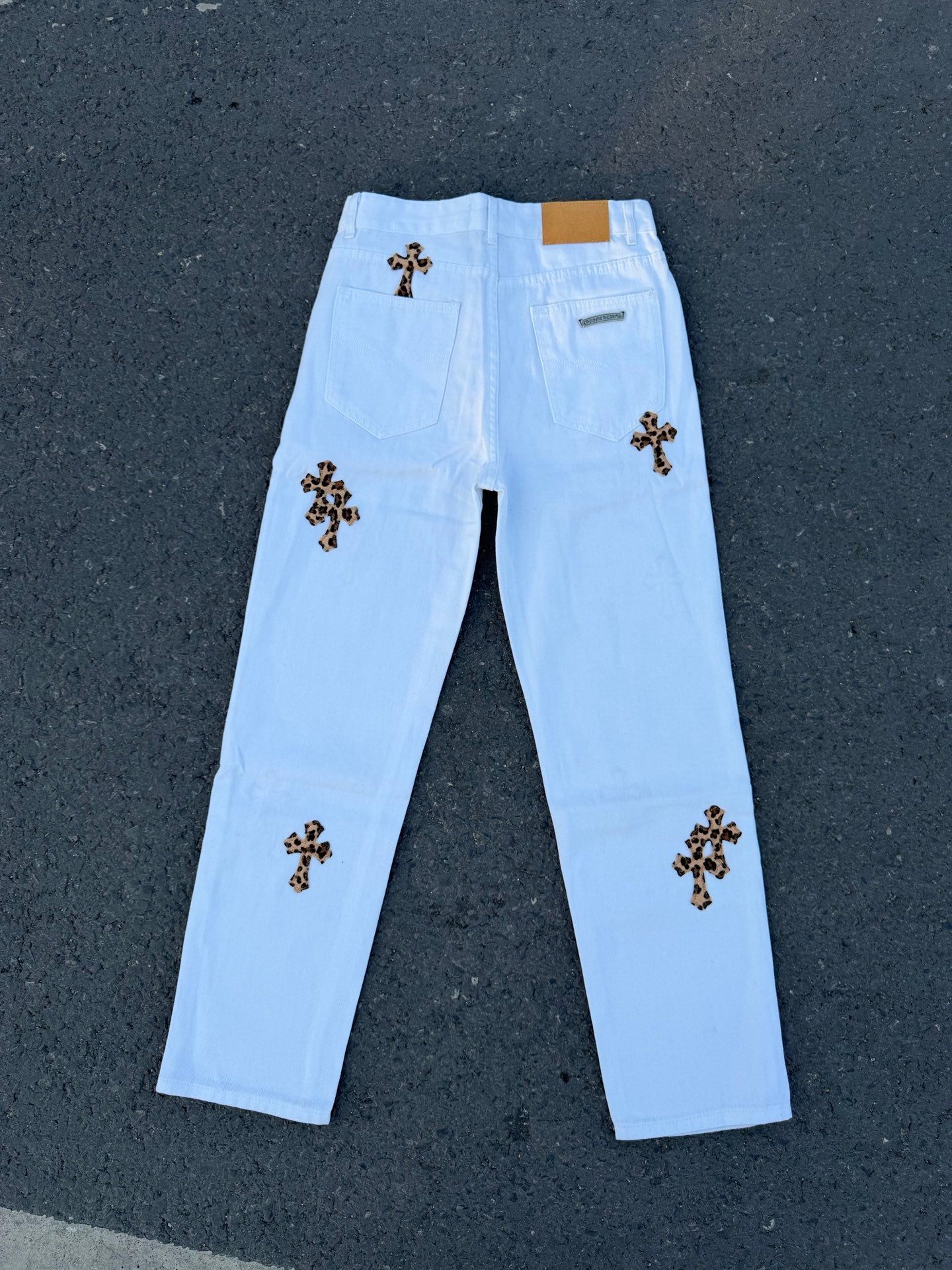Light blue straight pants with dark cross patches on front legs and back yoke