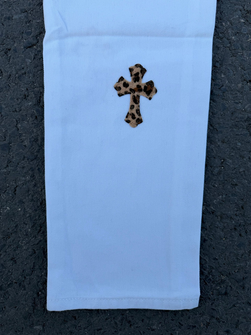 Light blue pants with small leopard-spotted cross graphic on front