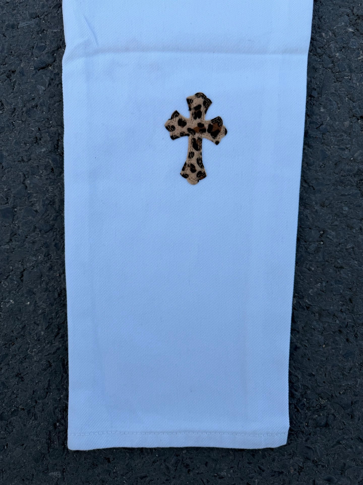 Light blue pants with small leopard-spotted cross graphic on front